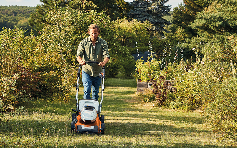 Man cutting lawn with the Stihl cordless lawn mower RMA 460 V in his garden